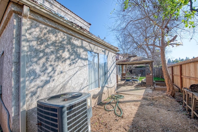 exterior space with central AC unit, a fenced backyard, a gazebo, a patio area, and stucco siding