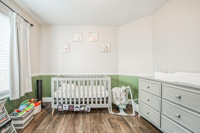 bedroom with a crib and wood finished floors