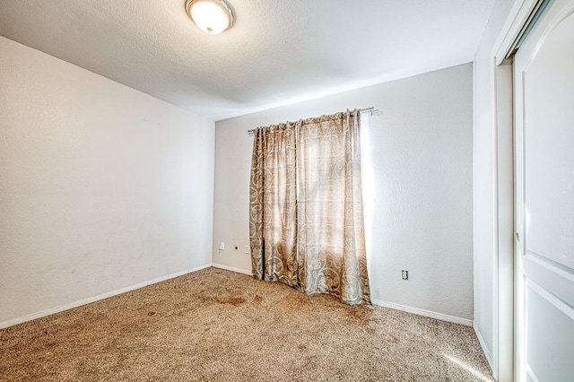 carpeted spare room with baseboards, a textured ceiling, and a textured wall