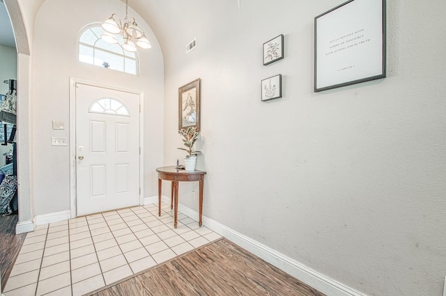 foyer entrance featuring arched walkways, light wood-type flooring, visible vents, and baseboards