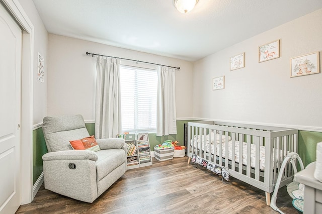 bedroom featuring a nursery area, a closet, and wood finished floors