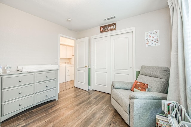 sitting room with visible vents, washer and clothes dryer, and wood finished floors