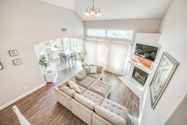 living room with arched walkways, a fireplace, baseboards, and wood finished floors