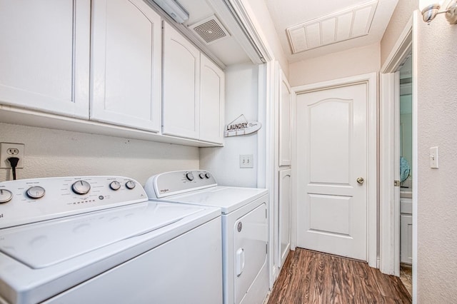 washroom with dark wood finished floors, visible vents, cabinet space, and separate washer and dryer