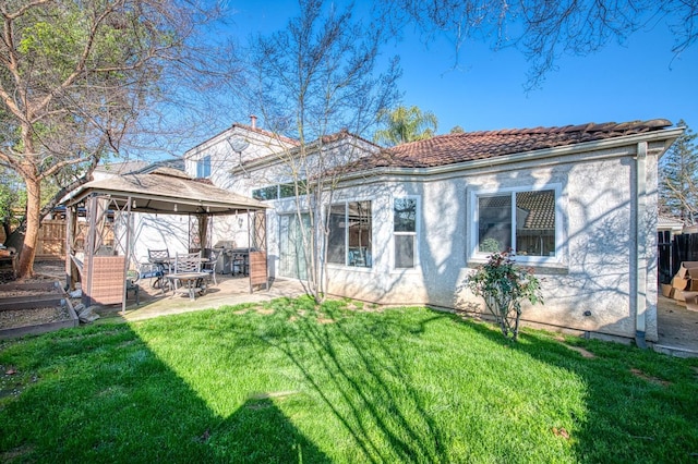 back of house featuring a patio, a tile roof, fence, a gazebo, and a yard