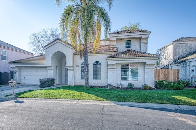 mediterranean / spanish-style house with driveway, an attached garage, fence, a front yard, and stucco siding