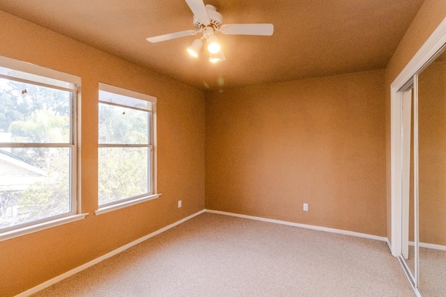 unfurnished room with baseboards, ceiling fan, and light colored carpet