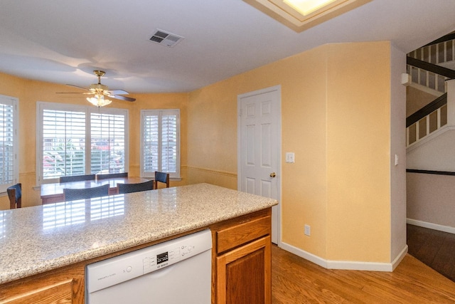 kitchen with visible vents, brown cabinetry, a ceiling fan, dishwasher, and light wood-style flooring