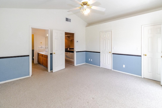 unfurnished bedroom with visible vents, baseboards, connected bathroom, light colored carpet, and vaulted ceiling