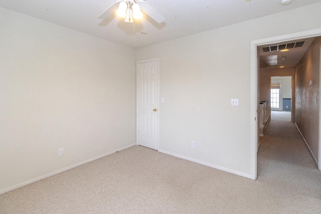 empty room with light carpet, baseboards, visible vents, and a ceiling fan