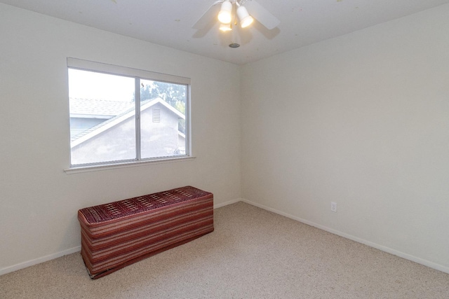 carpeted spare room featuring a ceiling fan and baseboards