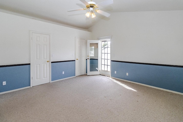 carpeted empty room featuring a ceiling fan, vaulted ceiling, and baseboards