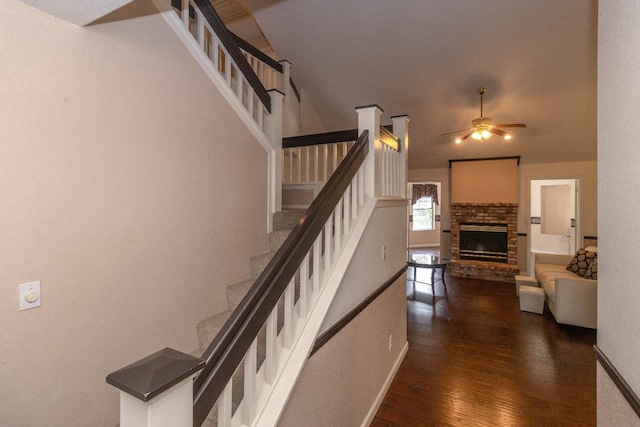 interior space with a brick fireplace, wood-type flooring, baseboards, and a ceiling fan