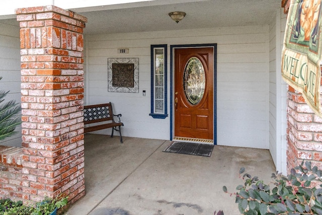 doorway to property with covered porch and brick siding