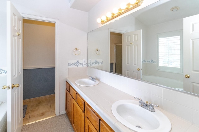 full bath featuring a tub to relax in, tile patterned flooring, a sink, and double vanity