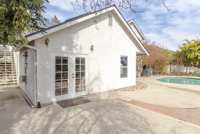 back of property featuring a fenced in pool, french doors, a patio, and stucco siding