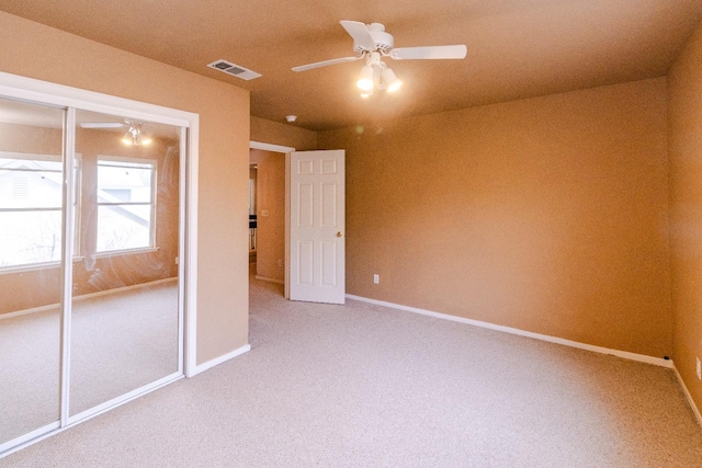 unfurnished bedroom with baseboards, visible vents, a ceiling fan, carpet, and a closet