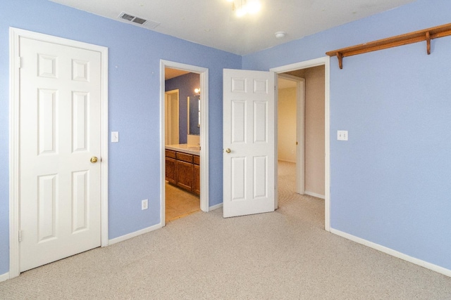 unfurnished bedroom with baseboards, ensuite bath, visible vents, and light colored carpet