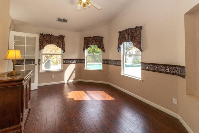 unfurnished room featuring a ceiling fan, visible vents, dark wood finished floors, and baseboards