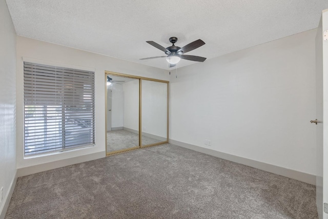 unfurnished bedroom featuring carpet, a closet, a ceiling fan, a textured ceiling, and baseboards