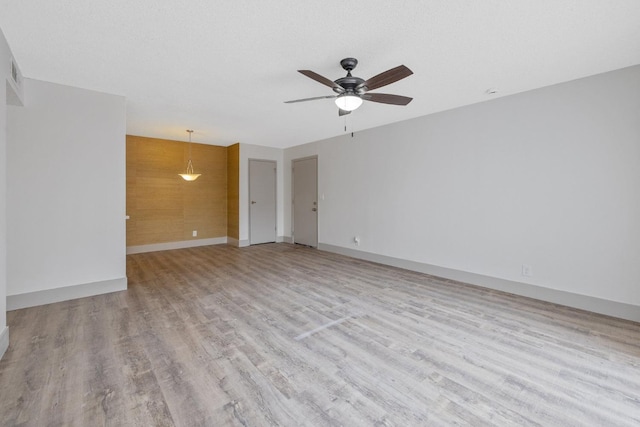 spare room with a textured ceiling, wood finished floors, a ceiling fan, and baseboards