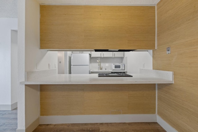 kitchen with a peninsula, white appliances, white cabinets, and a textured ceiling