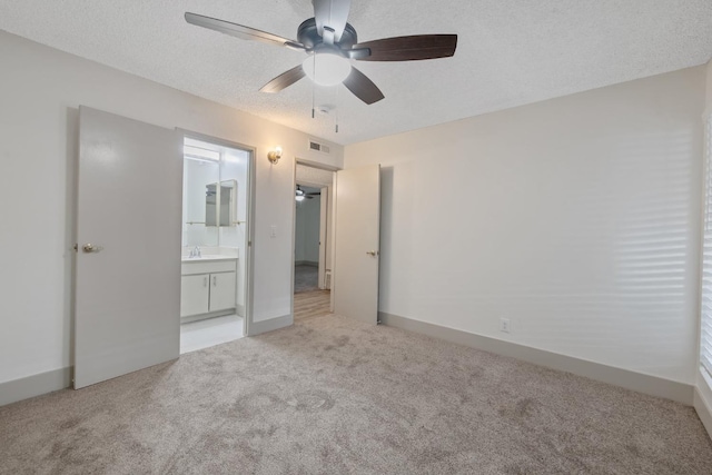 unfurnished bedroom with carpet floors, visible vents, a sink, a textured ceiling, and ensuite bath