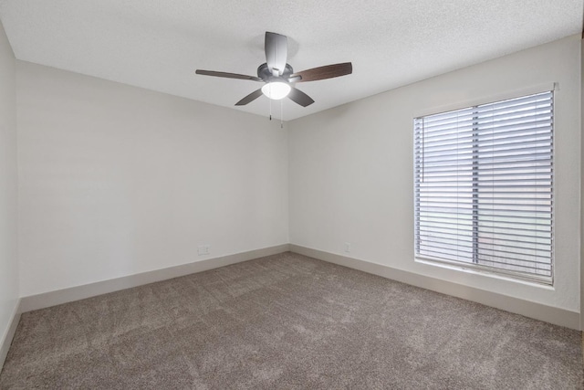 empty room featuring carpet floors, ceiling fan, a textured ceiling, and a wealth of natural light