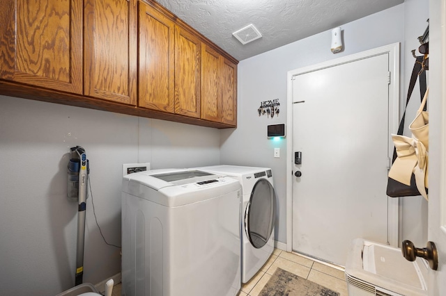 clothes washing area with cabinet space, visible vents, light tile patterned flooring, a textured ceiling, and washer and dryer