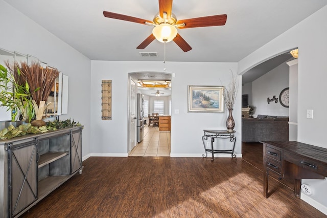 interior space with baseboards, visible vents, arched walkways, and wood finished floors