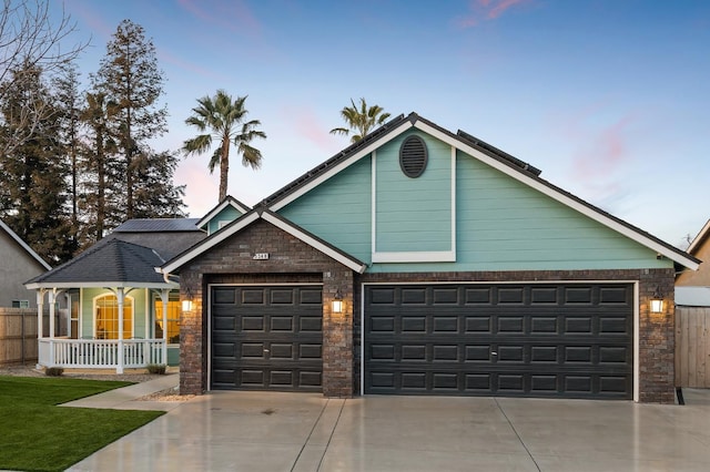 view of front of house with driveway, covered porch, a garage, and fence