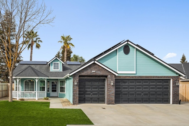 view of front of home featuring a porch, an attached garage, a front yard, roof mounted solar panels, and driveway