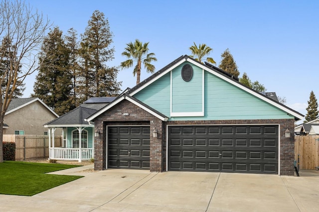 view of front of property with driveway, a porch, fence, and roof mounted solar panels