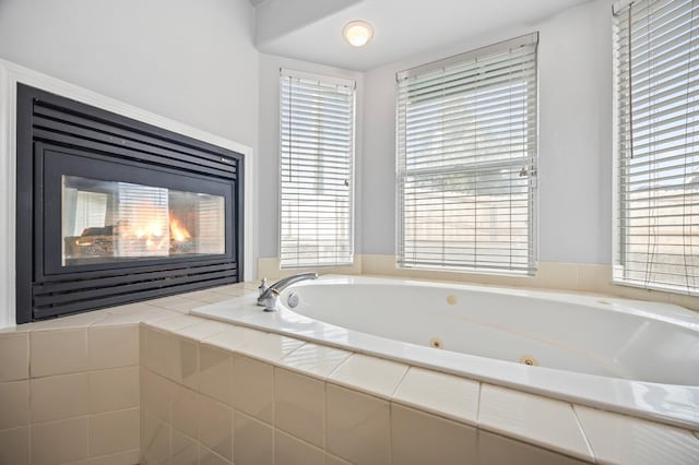 bathroom with a whirlpool tub and a glass covered fireplace