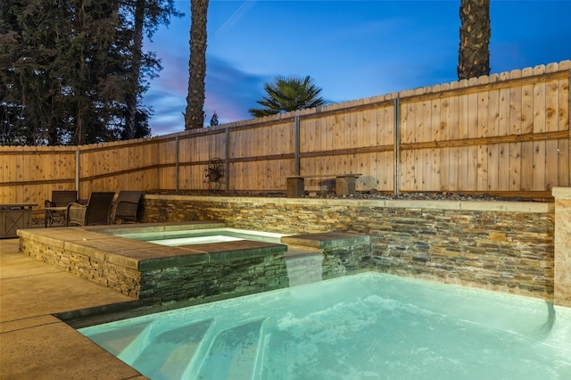 view of pool with fence and an in ground hot tub