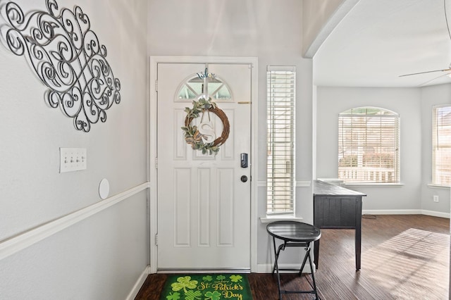 foyer entrance with dark wood-style floors, a ceiling fan, and baseboards