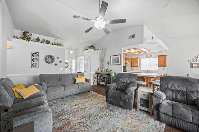 living area featuring vaulted ceiling, ceiling fan, wood finished floors, and visible vents