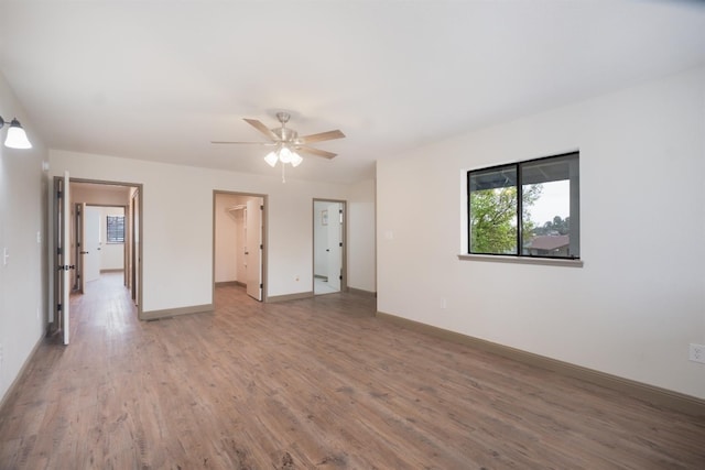 unfurnished room with a ceiling fan, baseboards, and wood finished floors