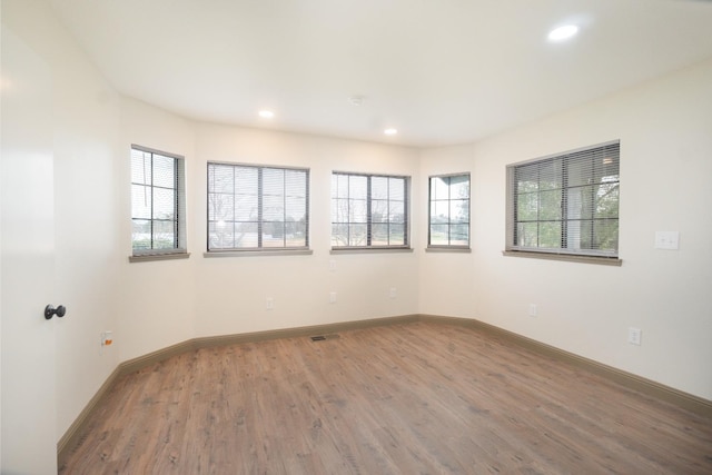 empty room with baseboards, wood finished floors, visible vents, and recessed lighting