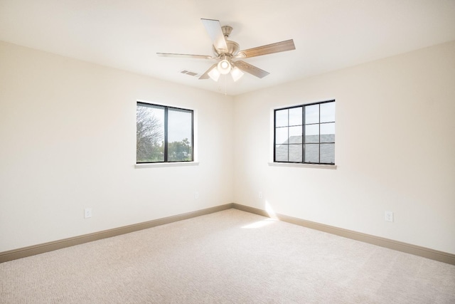 carpeted spare room with a healthy amount of sunlight, baseboards, and visible vents