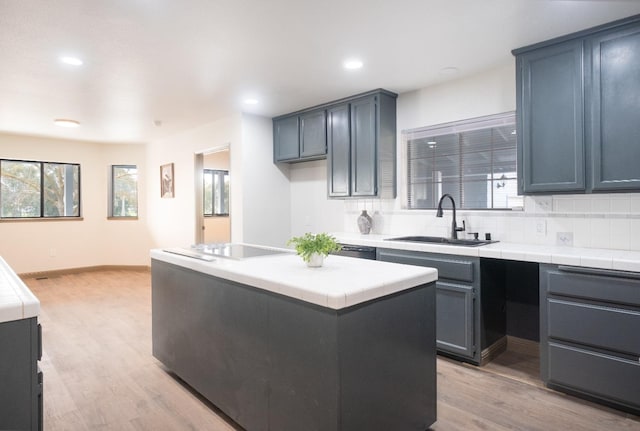 kitchen featuring backsplash, a sink, tile countertops, and light wood finished floors