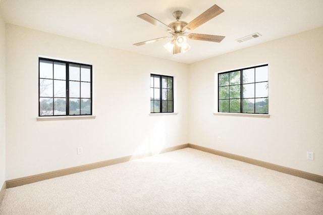 unfurnished room with carpet floors, baseboards, visible vents, and a ceiling fan