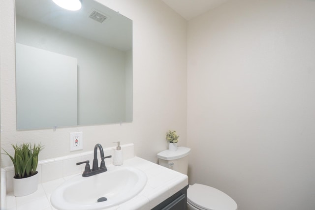 half bathroom featuring toilet, visible vents, and vanity