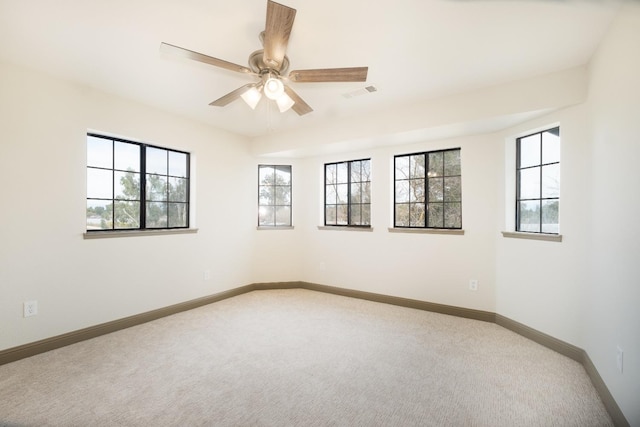 unfurnished room featuring baseboards, visible vents, ceiling fan, and light colored carpet