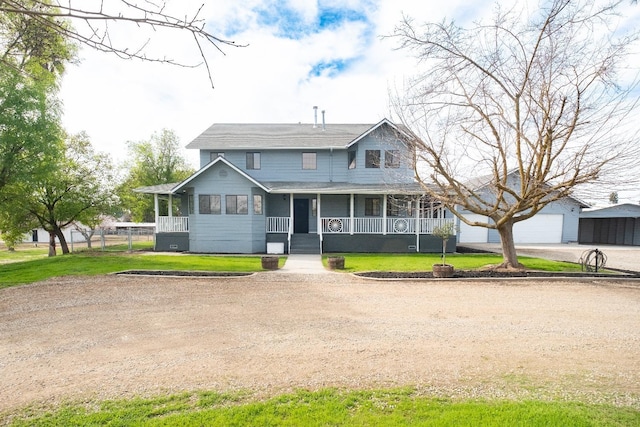 farmhouse inspired home with a porch, a front yard, an outdoor structure, and a detached garage