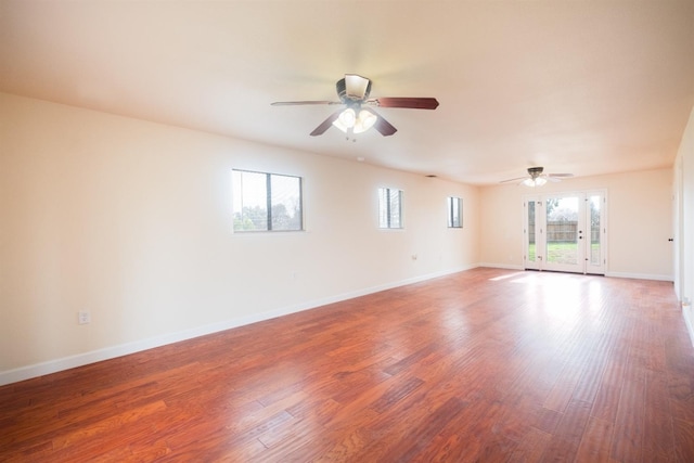 empty room featuring ceiling fan, baseboards, and wood finished floors