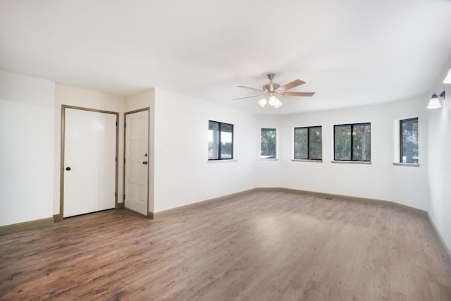 unfurnished room with wood finished floors, a ceiling fan, and baseboards