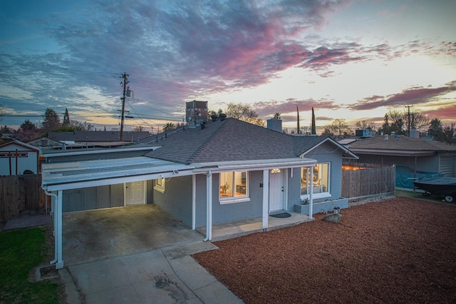 single story home featuring roof with shingles, stucco siding, concrete driveway, fence, and a carport