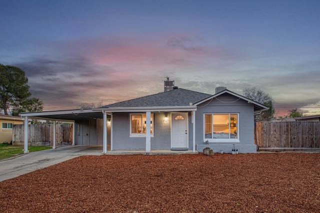 view of front of house featuring driveway, a shingled roof, fence, and a carport