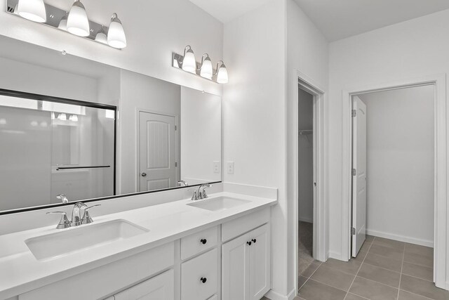 bathroom featuring tile patterned flooring, a sink, baseboards, and double vanity